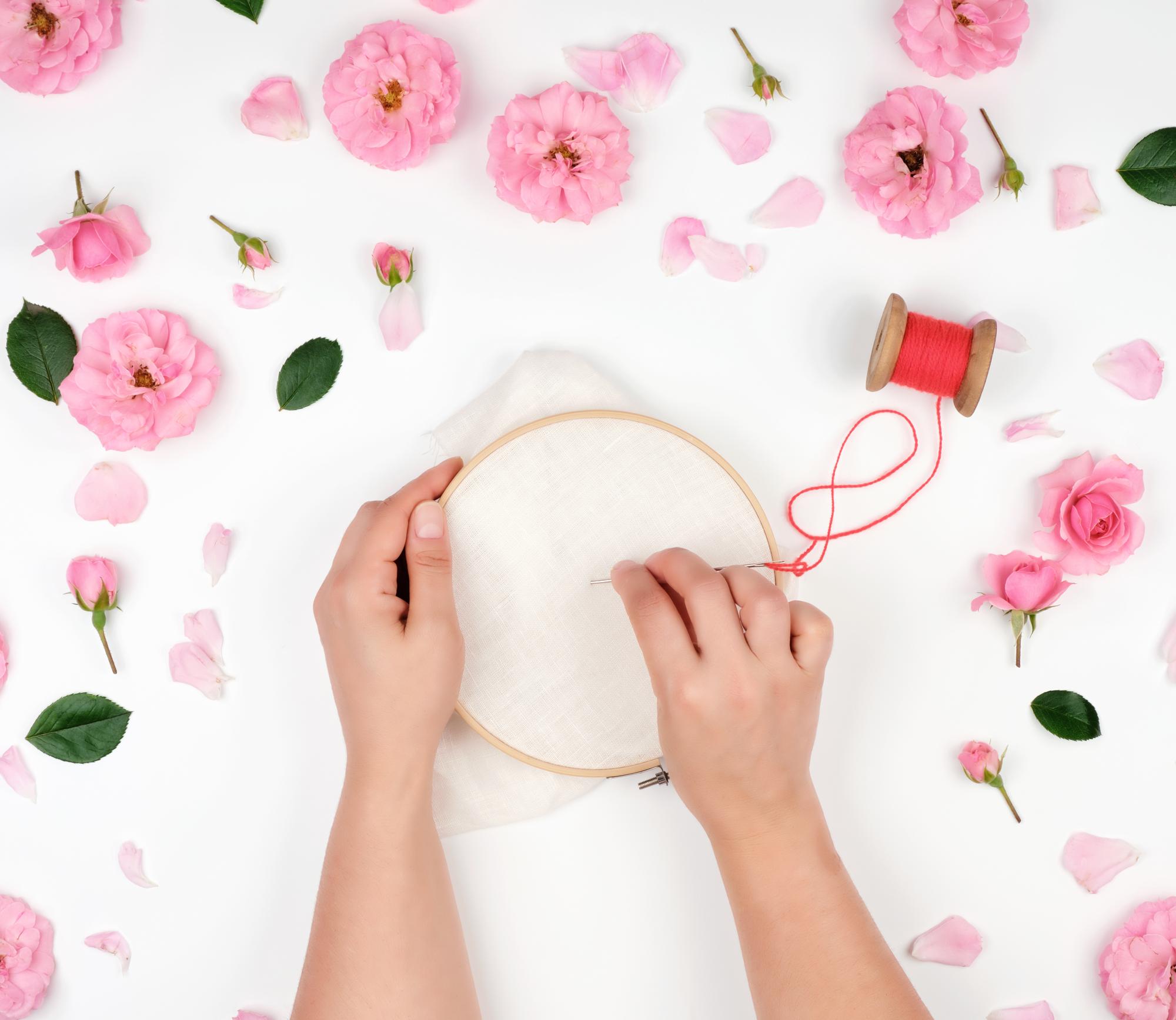 Hands embroidering floral motif